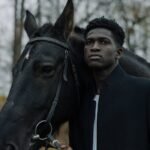 Serene portrait of a man with a horse in an outdoor setting.